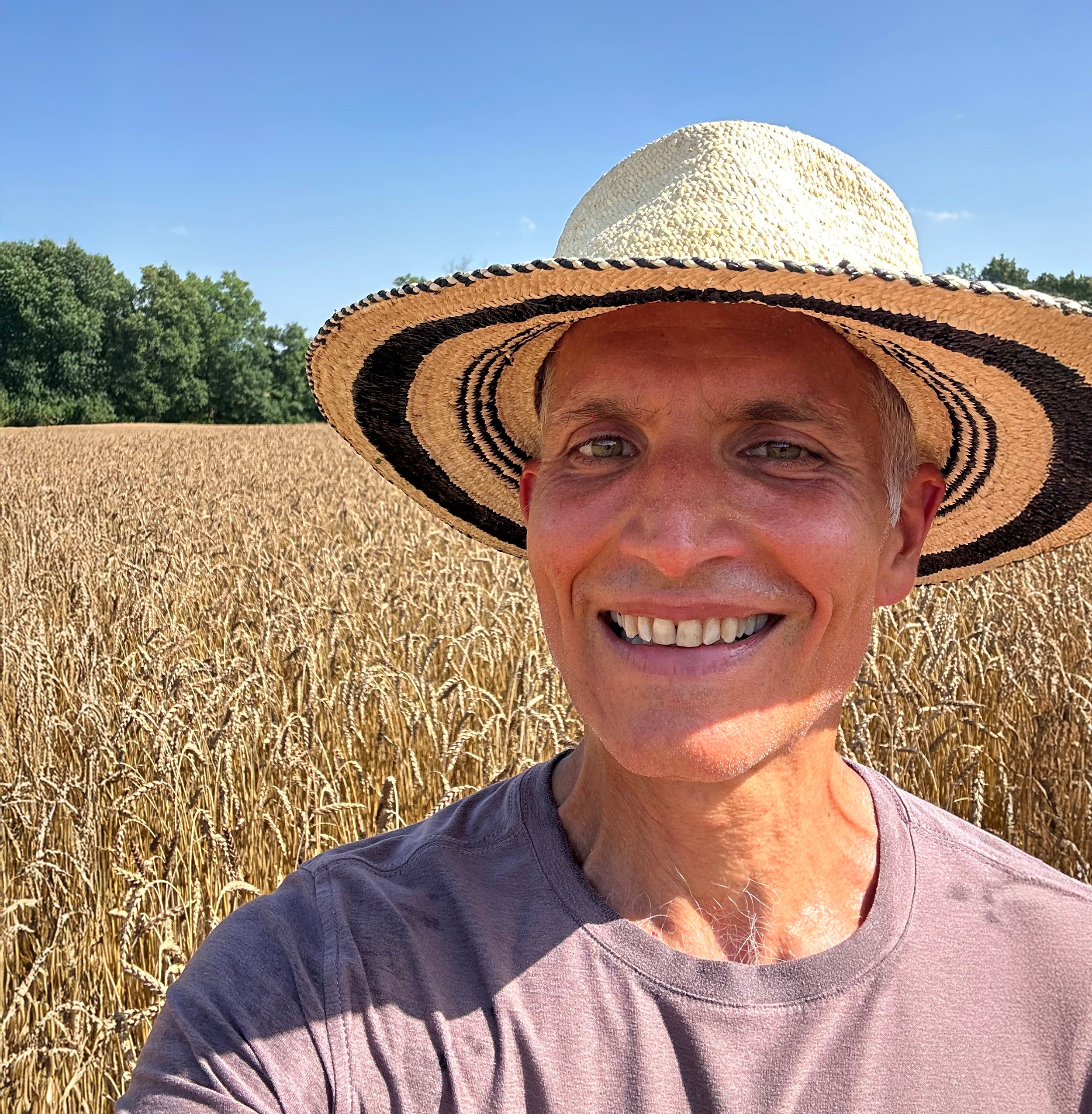 Jason Deslavo wearing a hat in the middle of a rouge de bordeaux wheat field at cold brook farm