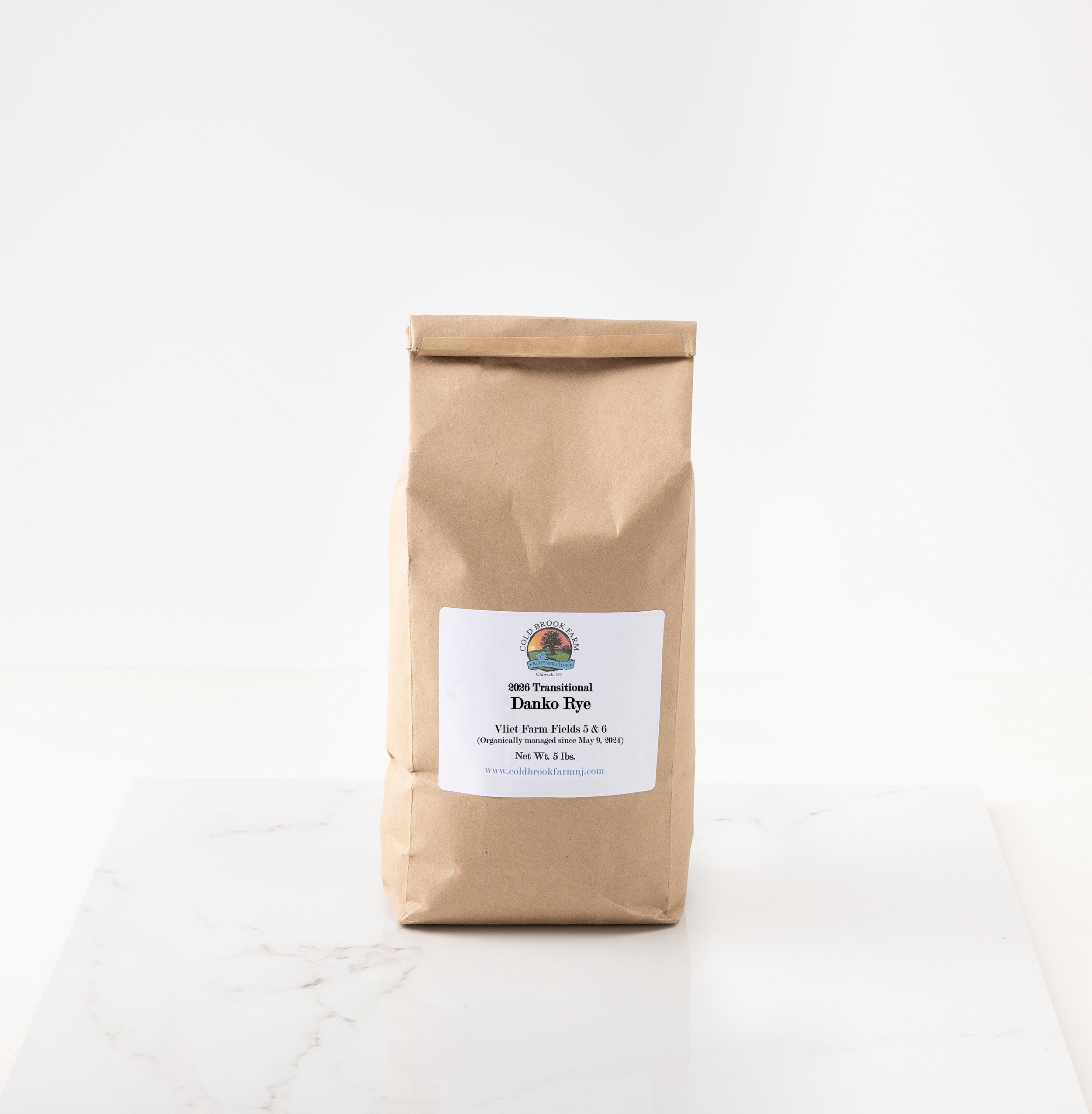 A brown kraft paper bag of 2026 Danko Rye standing on a white marble surface against a white background.