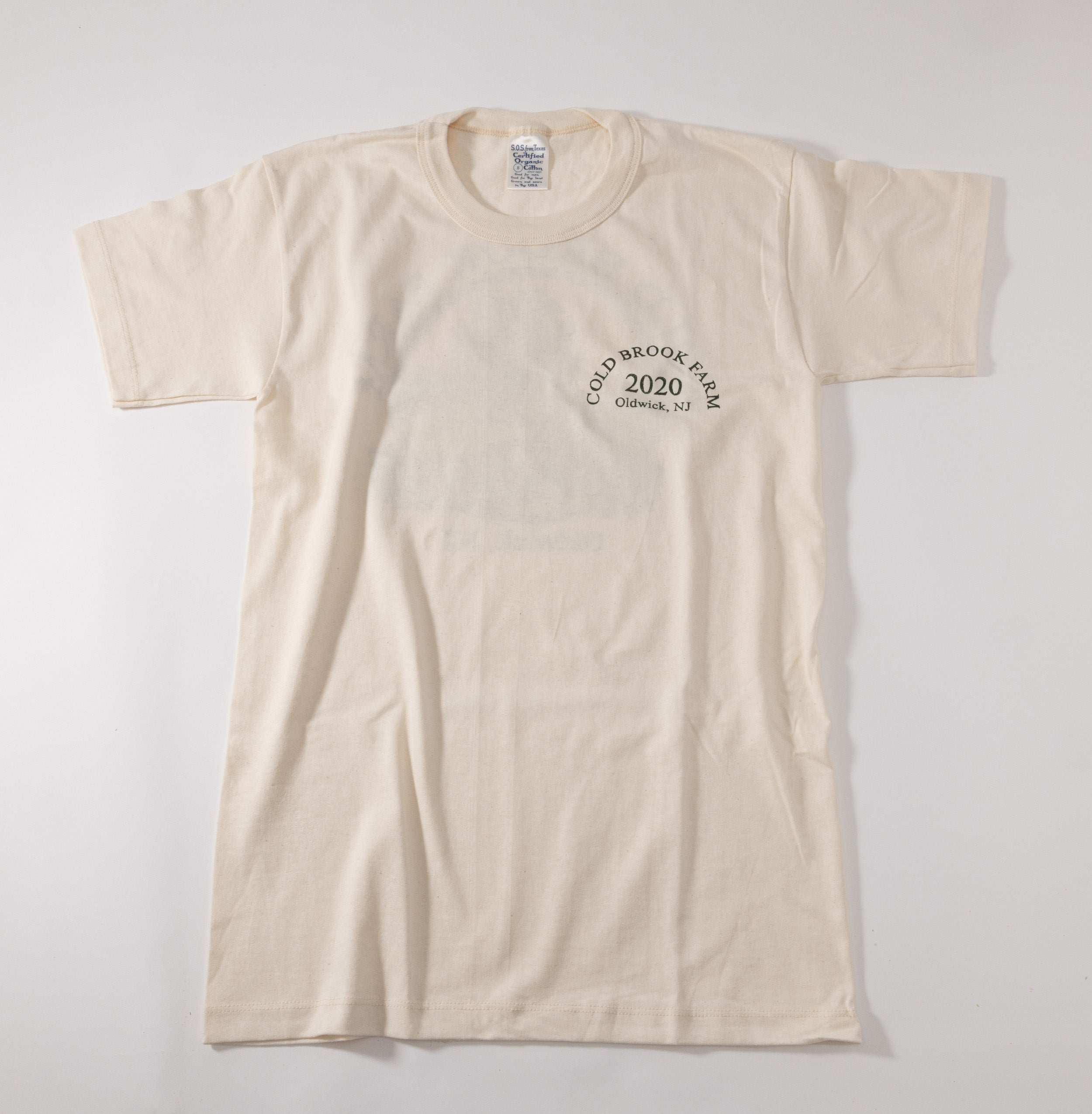 An off-white short-sleeve t-shirt with a small dark circular graphic on the left chest reading 'COLD BROOK FARM 2020 OLDWICK, NJ'