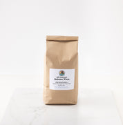 A brown kraft paper bag of 2026 redeemer wheat featuring a white label with the brand logo, set on a white marble surface against a white background.